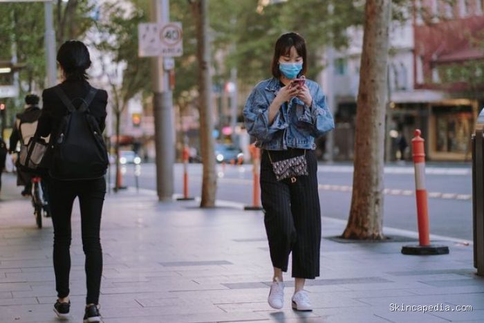 Perempuan berjalan di trotoar sambil mengirim pesan/ Foto: Pexels.com/Kate Trifo
